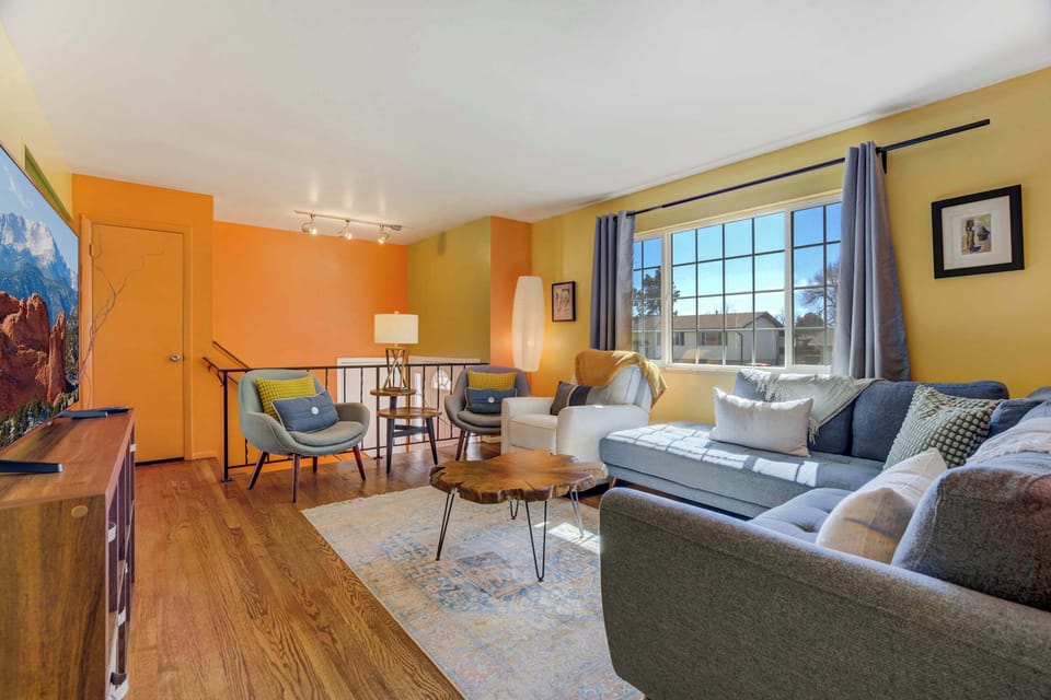Sunlit living room with a big sectional and cozy chairs—stretch out after a day out, put your feet up on the rug, and linger over coffee around the round table while light pours in through the large window.