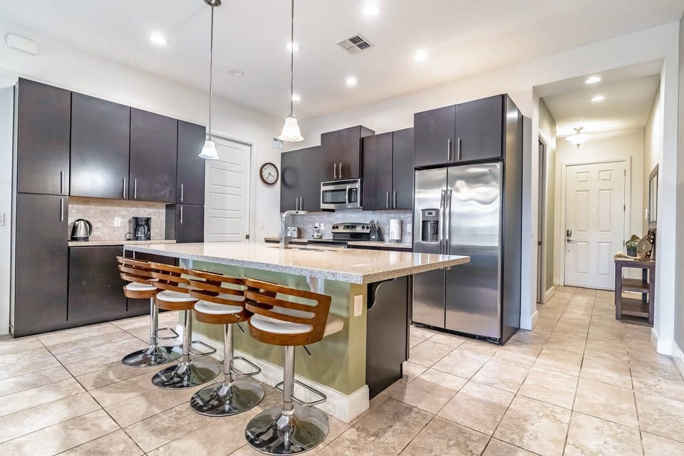 Fully stocked kitchen with stainless steel appliances and island seating for 4