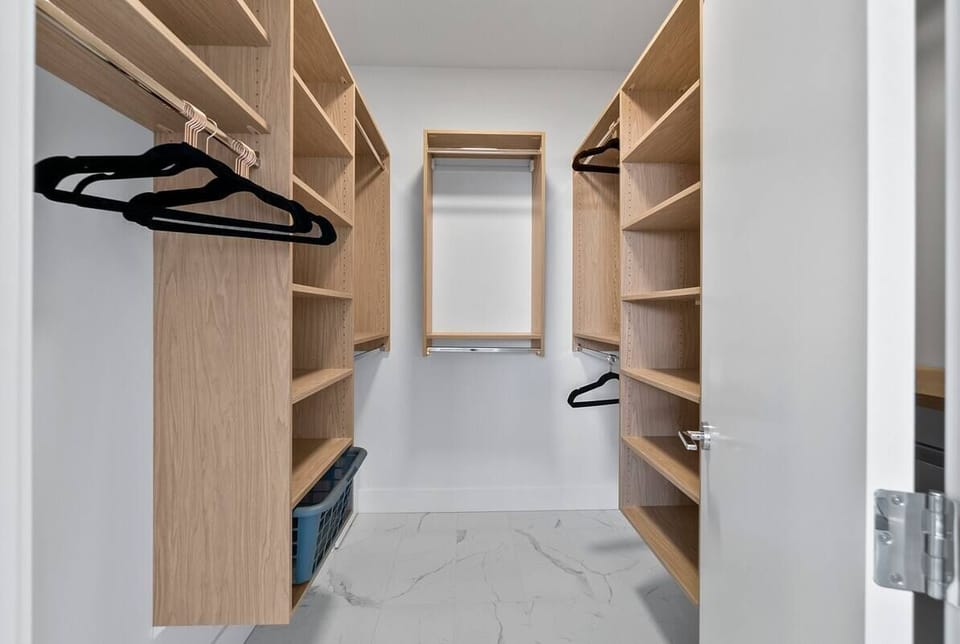 Walk in closet neatly holds clothes, shoes, and accessories in this walk-in closet, offering a practical yet organized space.