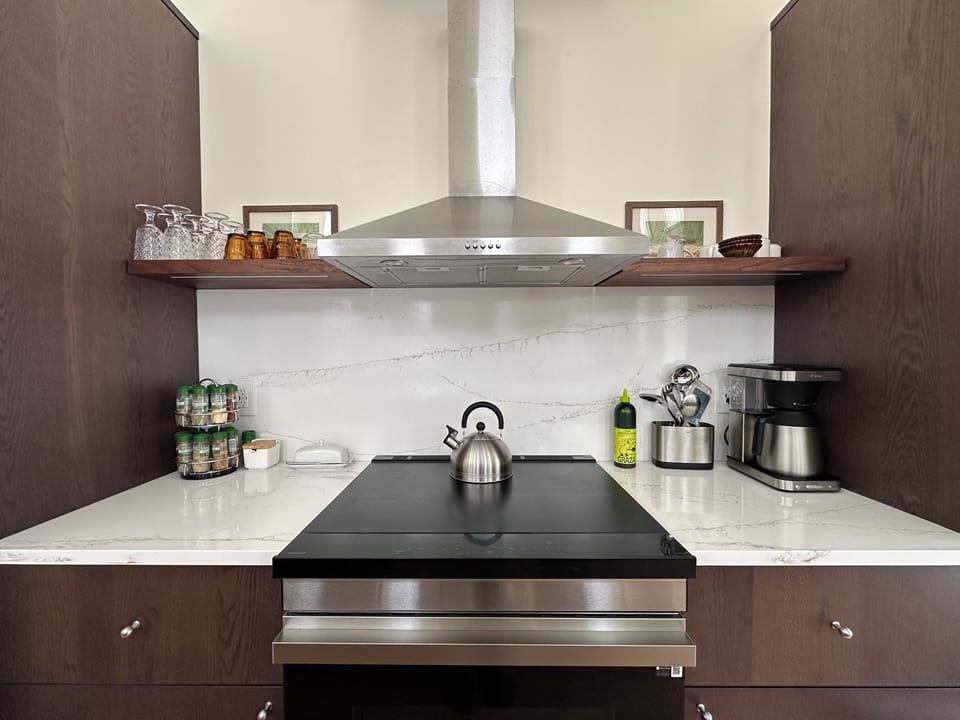 spacious, clean kitchen with range, teapot, cups, spices, and more