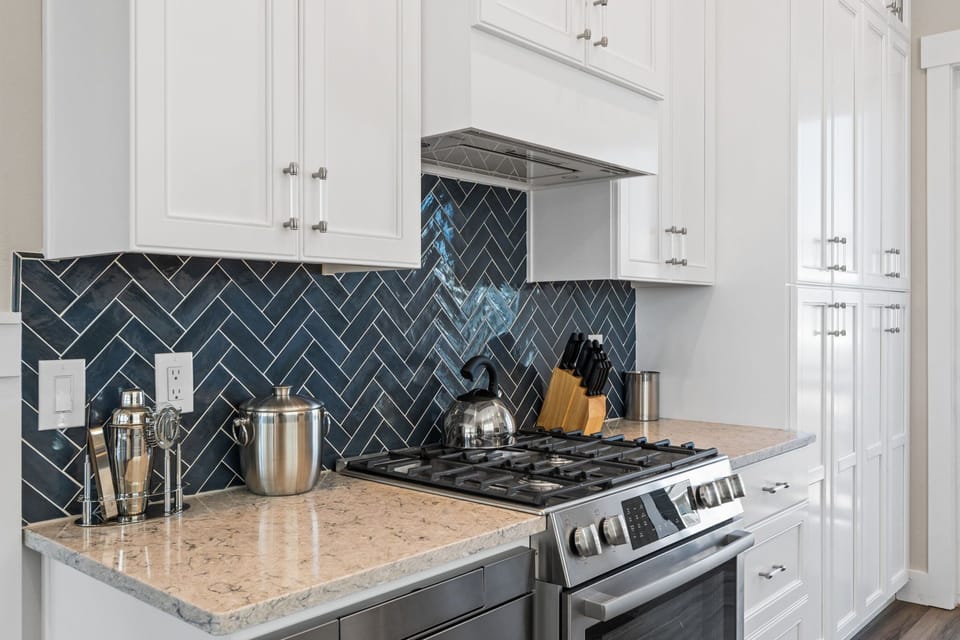 Your modern kitchen features sleek white cabinets, stunning herringbone backsplash, and granite counters perfect for preparing memorable meals together.