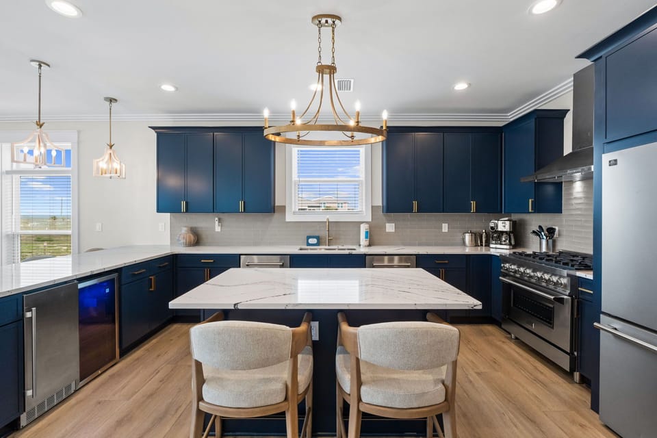 This spacious kitchen welcomes you with rich navy cabinetry, gleaming marble-topped island, and abundant natural light. Prepare meals on professional-grade appliances while enjoying beautiful views through the windows.