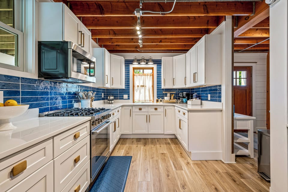 Bright kitchen with white cabinets, appliances, and wooden ceiling.