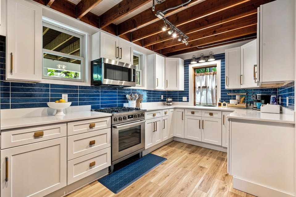 Bright kitchen with white cabinets, appliances, and wooden ceiling.