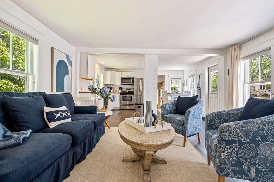 Bright sunroom living room with blue sofa and patterned chairs.