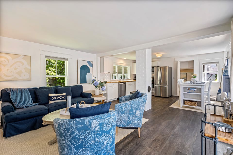 Bright sunroom living room with blue sofa and patterned chairs.