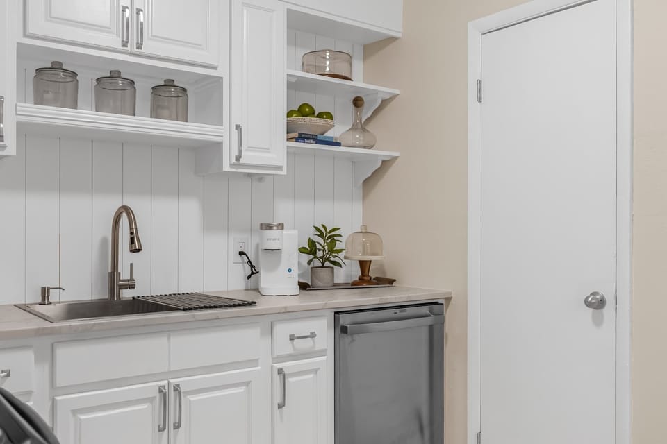 Modern kitchen corner with white cabinetry, stainless steel sink, and built-in dishwasher.