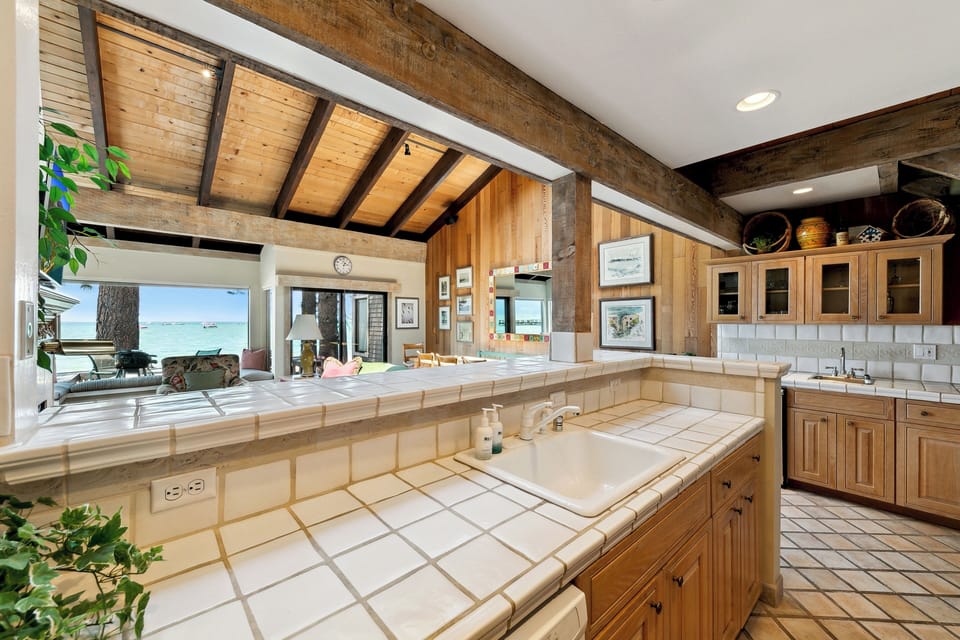 Cook with stunning ocean views from this beautifully crafted kitchen featuring warm wood cabinets and exposed beam ceilings.