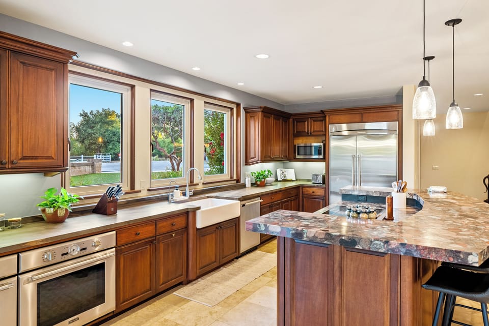Prepare gourmet meals in this stunning high-end kitchen! Featuring warm wood cabinetry, stainless appliances, and a massive granite island, this bright space is the heart of the home.