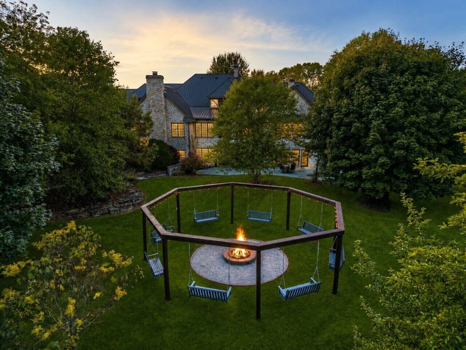 The octagonal fire-pit circle is surrounded by suspended bench swings for group evenings outdoors.
