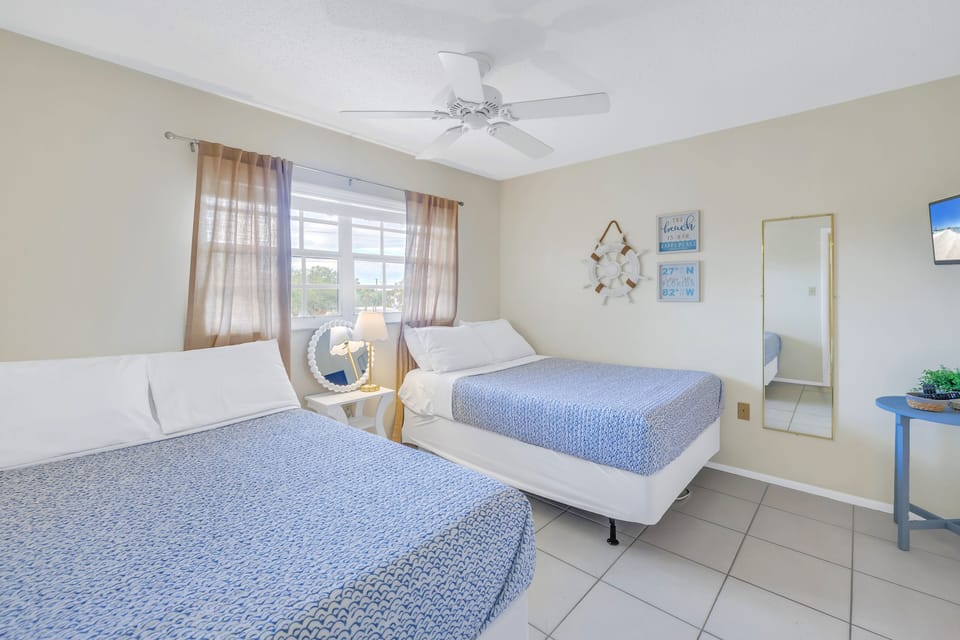 Double queen bedroom with window looking out to sunshine.