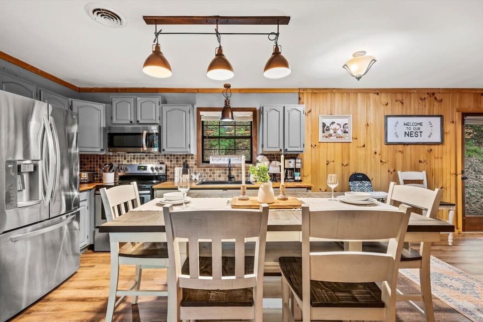 Open-concept kitchen and dining with wood-paneled walls, modern appliances, and a welcoming atmosphere, perfect for gatherings and shared moments.