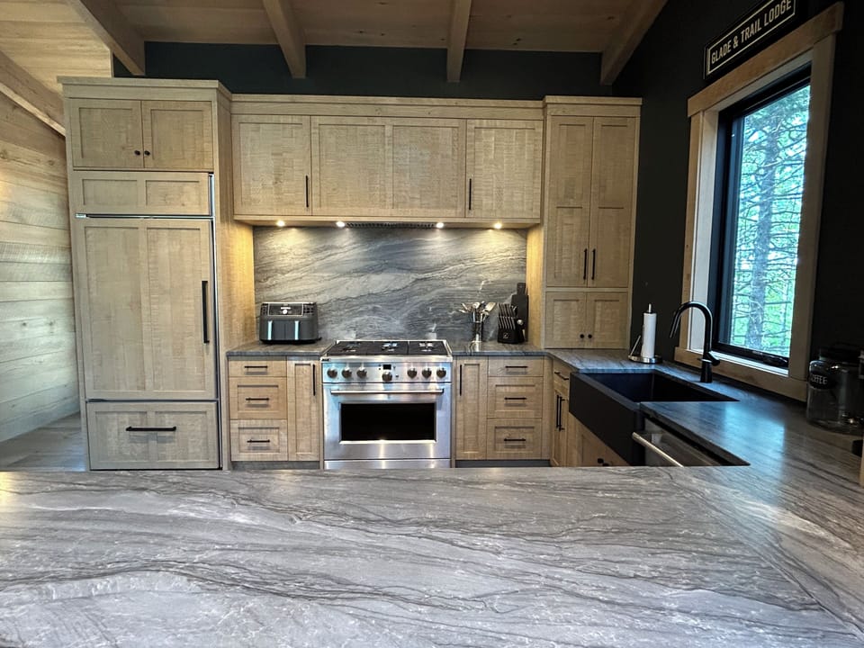 Kitchen w/gas range & fridge wall, rough sawn cabinetry, natural quartzite stone