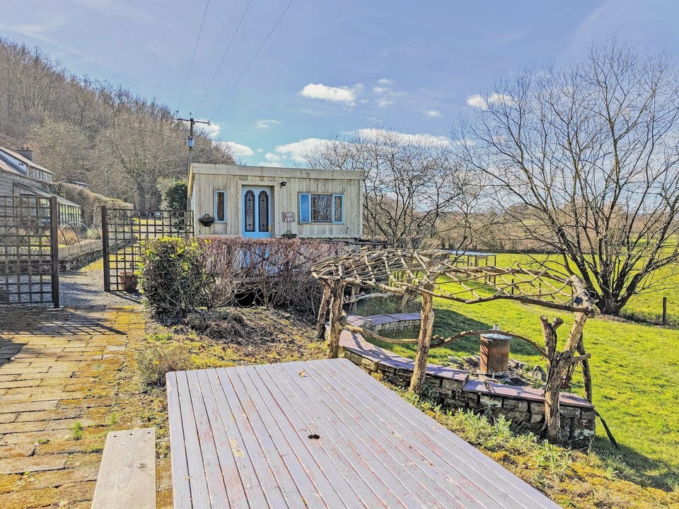 Outdoor table and benches, including arch seating area with fireplace | Rosie - Tanyrallt Holidays Lets, Llanybydder, near Lampeter