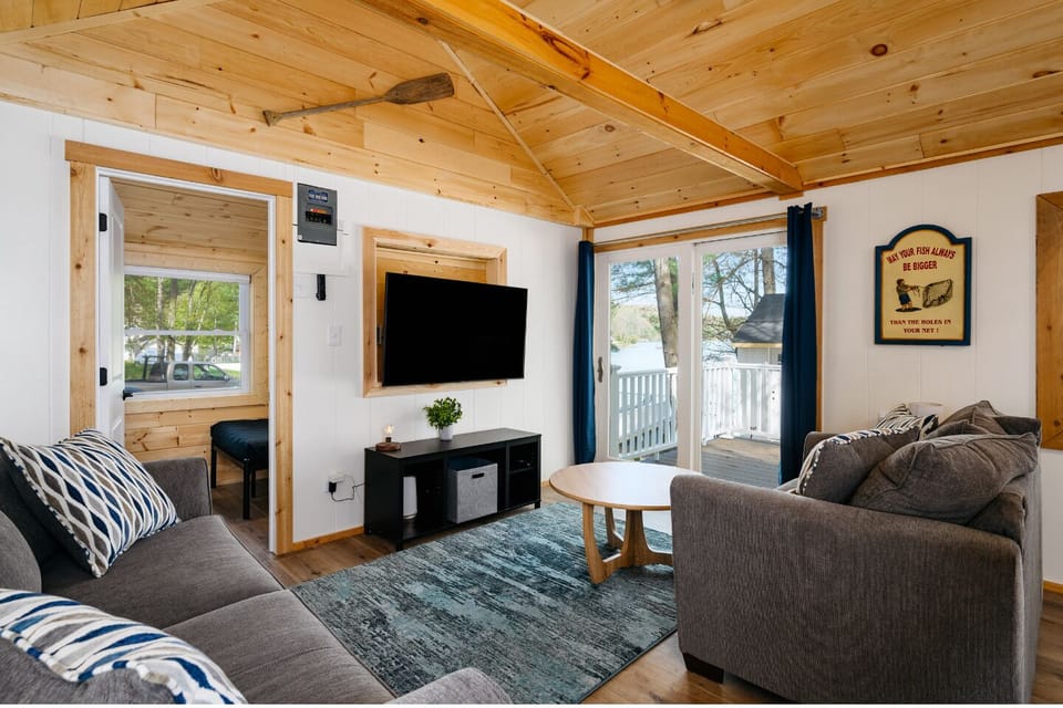 Cozy up in this inviting living room with stylish sofas — perfect for unwinding with your favorite shows, all while soaking in serene lake views framed by tall pines 🌲✨