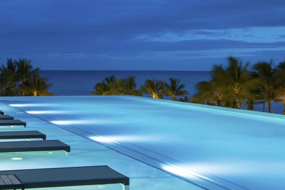 Drift through twilight waters as palms glow softly below.