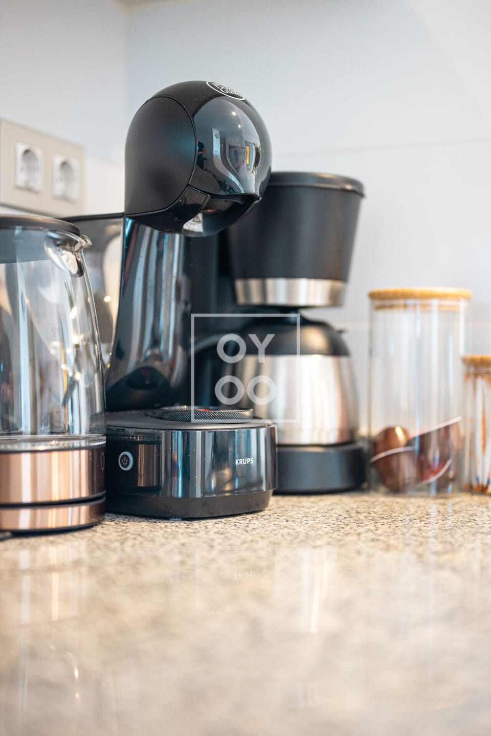 Chic coffee corner equipped with a Krups espresso machine, drip brewer, and stylish glass canisters—your morning ritual just got an upgrade. Granite countertop adds a sleek, durable touch ☕🔌