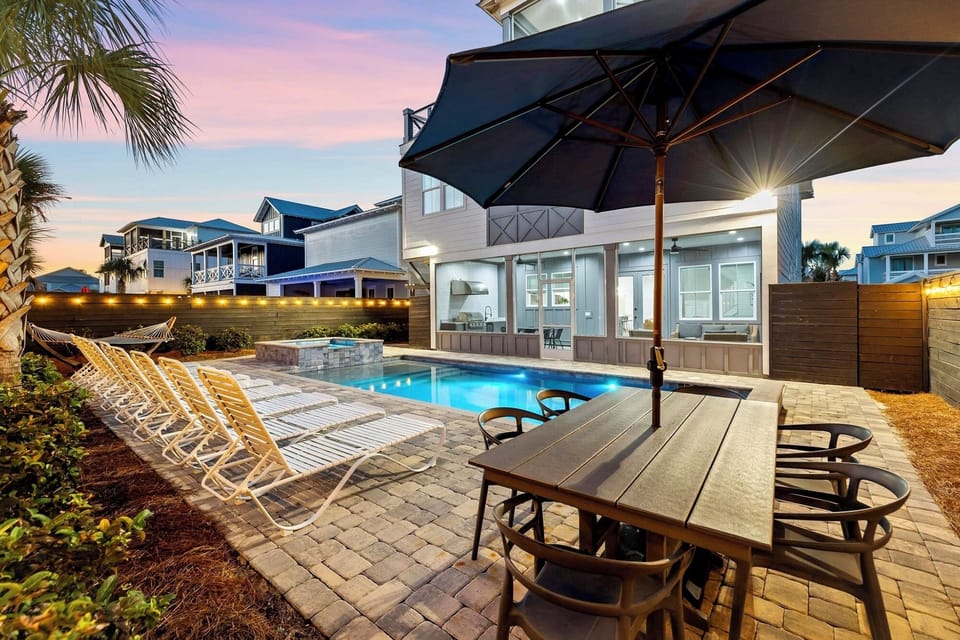 Private backyard oasis with heated pool, hot tub, lounge chairs, hammock, outdoor dining table, corn hole and a screened in outdoor kitchen, dining, and lounge area!