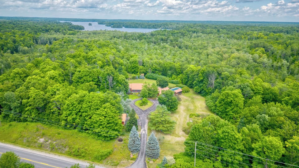 A red-roofed house sits in a clearing surrounded by trees.