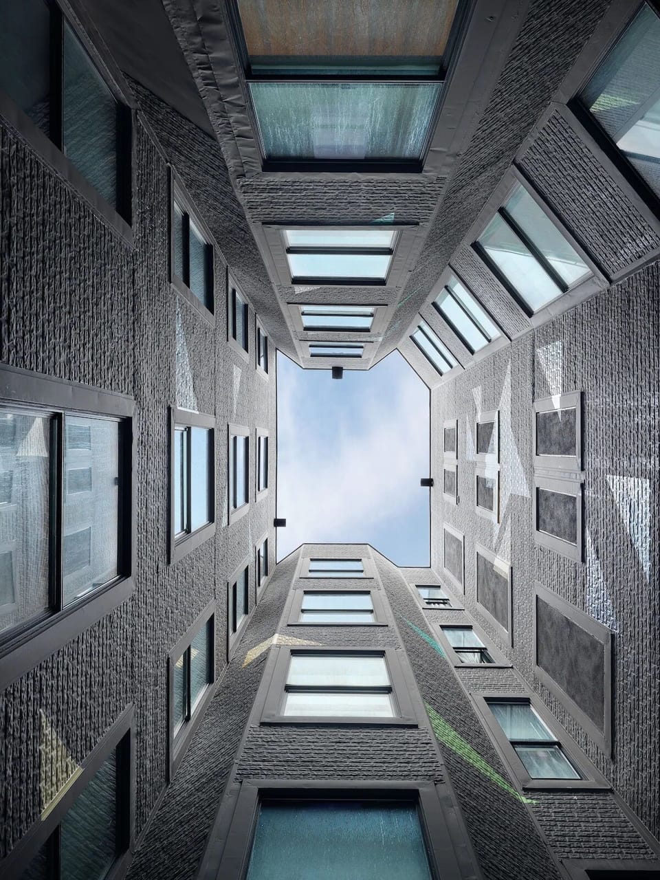 Look up to a serene courtyard lightwell and quiet symmetry.