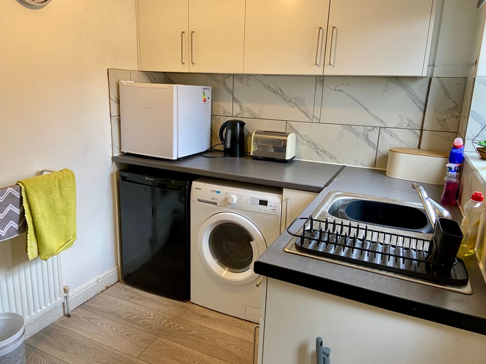 Kitchen with wahing machine, mini fridge and freezer.