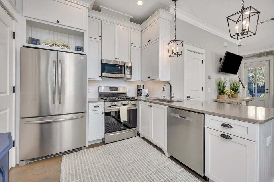 Kitchen with stainless appliances, white cabinets, and pendant lights
