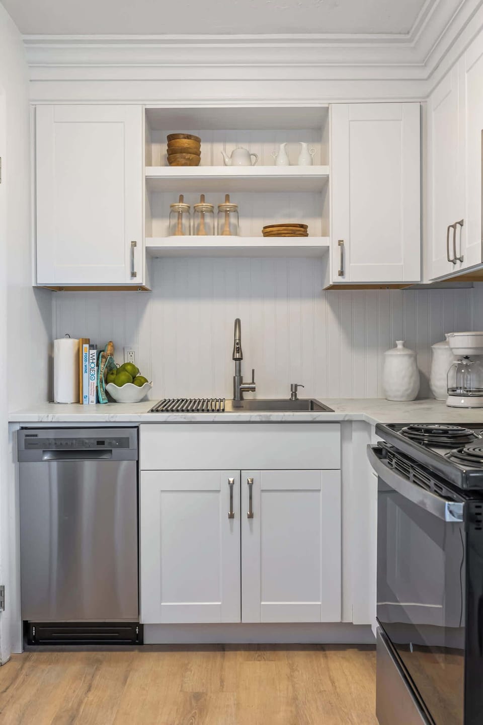 Modern kitchen sink area with white cabinetry and stainless steel appliances