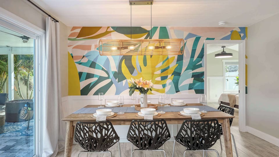 Gather beneath a modern pendant and bold botanical mural—this space is made for family-style dining and connection.