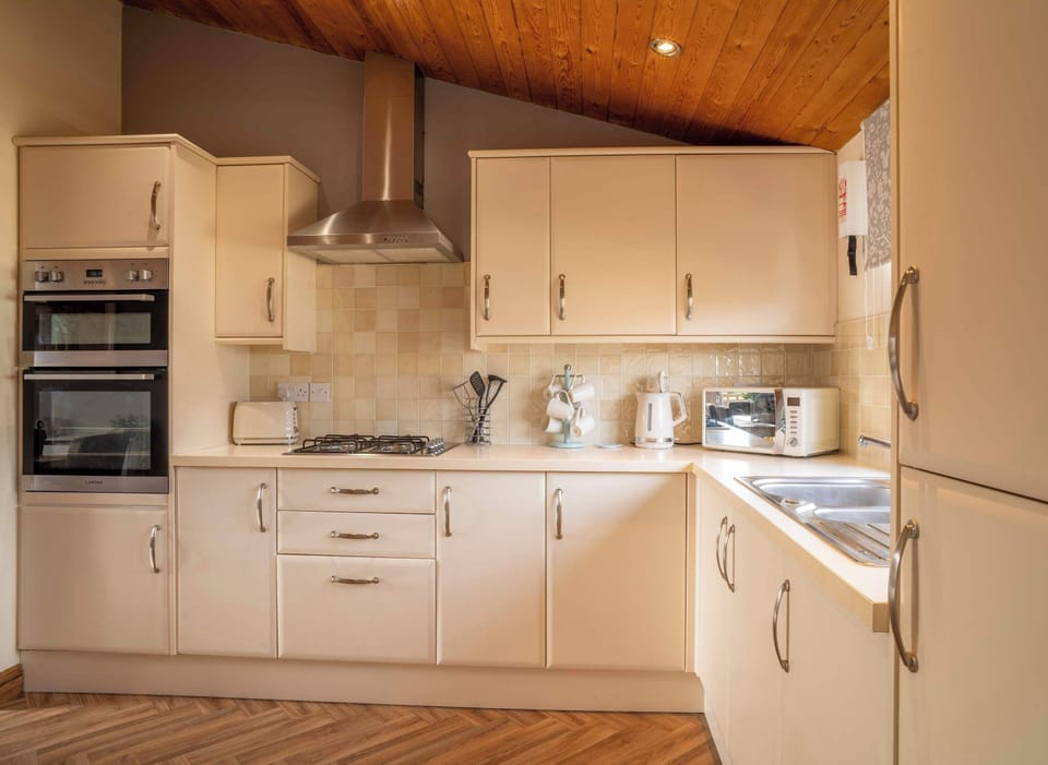 Cook up memories in a chic, fully equipped kitchen featuring modern appliances, stylish tiling, and warm wood accents.