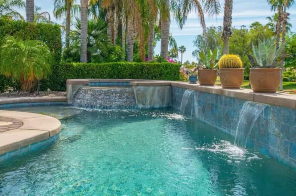 Cascading waterfall pool framed by lush palms & vibrant desert gardens