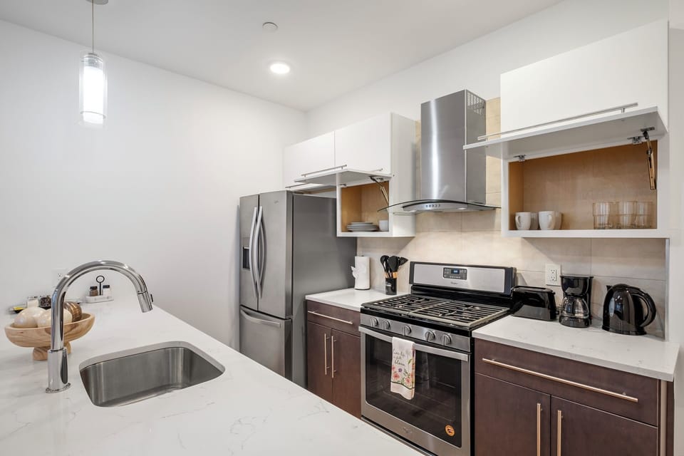  Full kitchen with stainless refrigerator, white cabinets, and modern appliances providing all the tools for delicious meals.