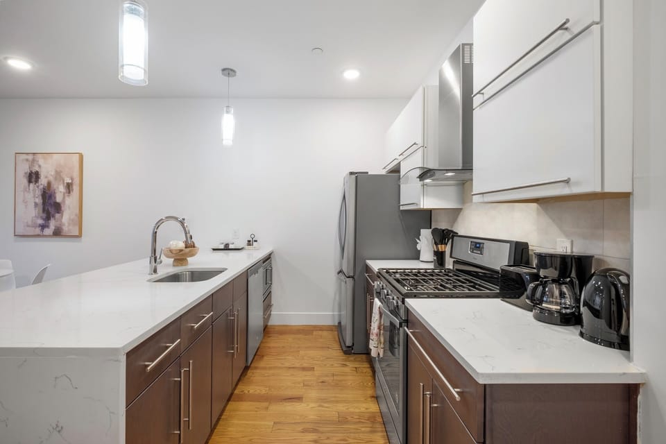Fully-equipped kitchen with modern white cabinets, stainless appliances, and granite counters ideal for preparing home-cooked meals.