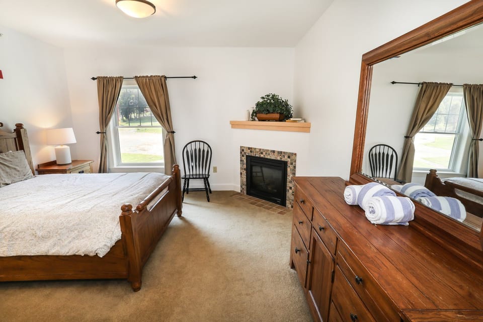 Spacious bedroom with elegant furnishings, soft lighting, and a cozy fireplace for added comfort.