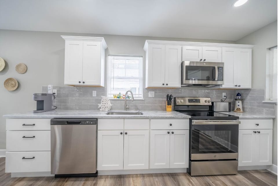 Modern and fully equipped, this sleek kitchen features stainless steel appliances, crisp white cabinetry, and all the essentials to whip up delicious meals. A stylish and functional space for cooking, gathering, and making lasting memories.