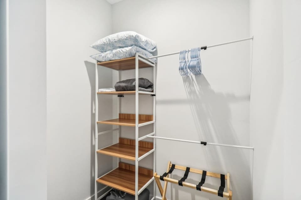 Large walk-in closet (his and her) with hangers, storage shelves and suitcase holder.
