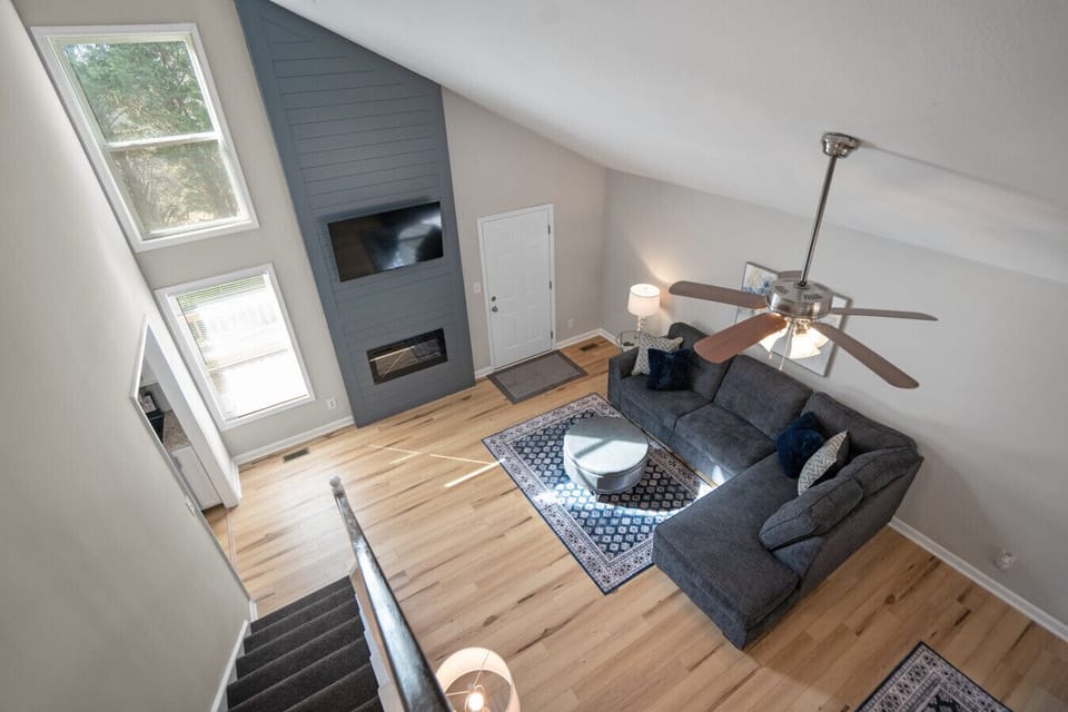 Staircase view overlooking the living room with vaulted ceilings and fireplace feature wall