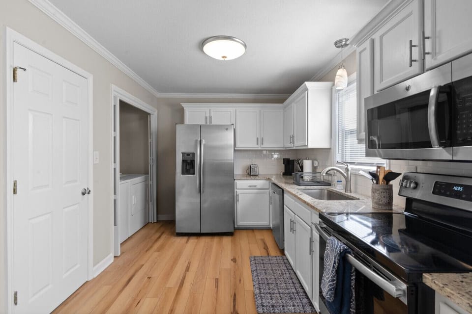 Fully equipped kitchen with stainless steel appliances, ample counter space, and adjacent laundry access
