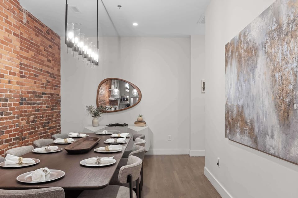 Stylish dining area with seating for eight, exposed brick detailing, and modern lighting—ideal for group meals or celebrating special moments.