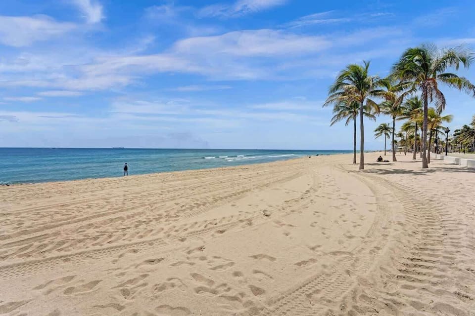 Fort Lauderdale beach with open sand, palms and calm ocean water.