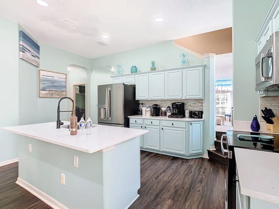 - Cook like a pro in this serene, mint toned kitchen with stainless steel appliances
- Enjoy ample counter space, a sleek island with pull down faucet, and modern lighting
- Morning brews are a breeze with the fully stocked coffee station ready for you