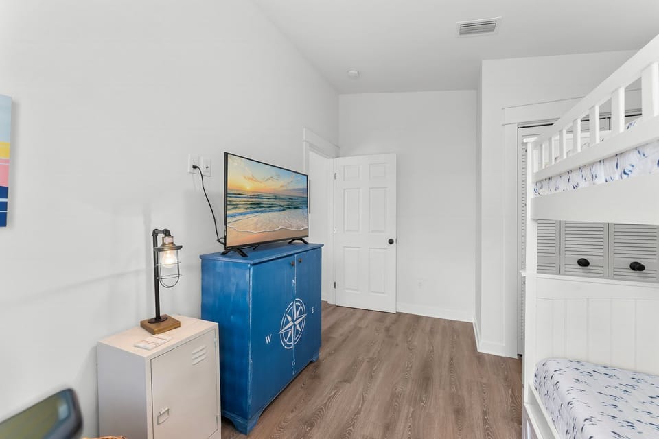 A simple room featuring a bunk bed and a television on a blue cabinet with a compass design.