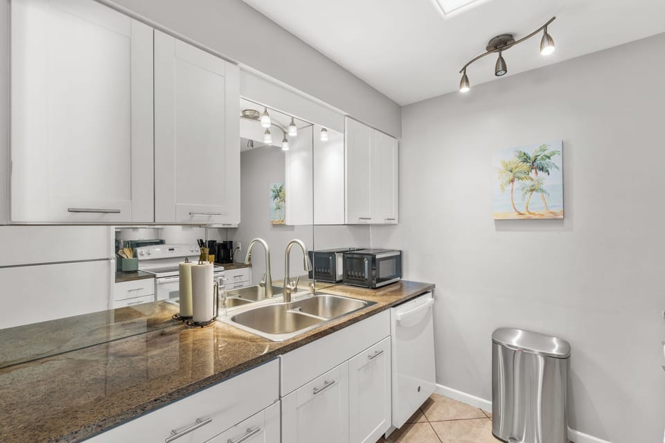Kitchen with granite countertops, modern appliances, and white cabinetry.