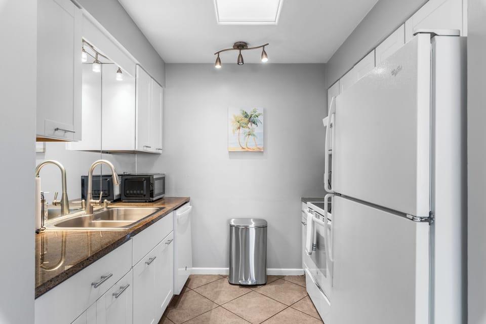 Kitchen with granite countertops, modern appliances, and white cabinetry.