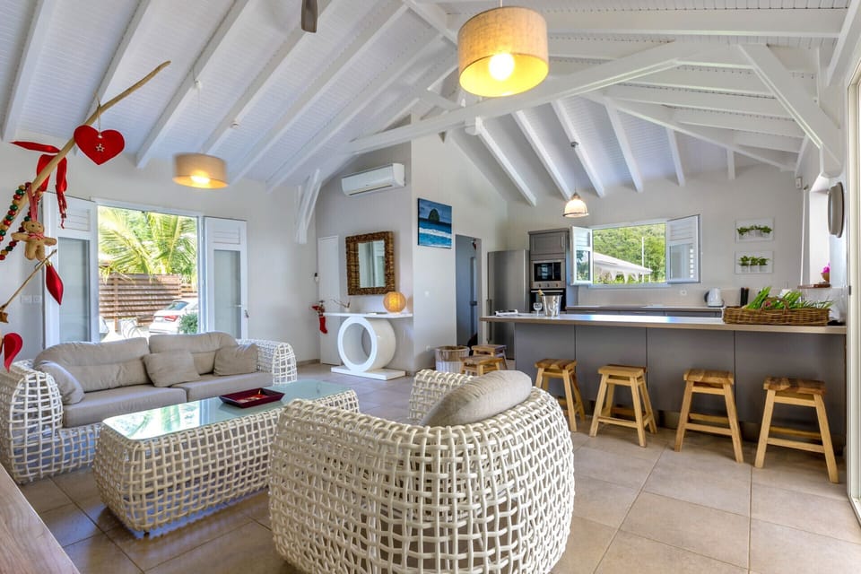 The kitchen and living room come together to create a spacious living area, under a beautiful beamed roof structure that reinforces the tropical personality of the One The Rock villa.