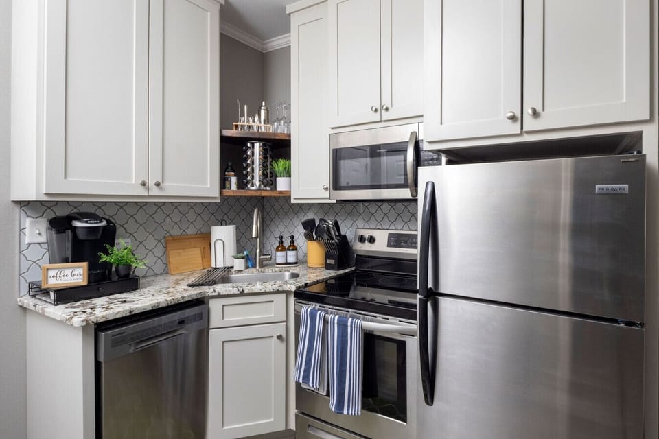 Modern kitchen with ample cabinets and a stainless steel refrigerator, fully stocked with kitchen essentials — perfect for home-cooked meals.