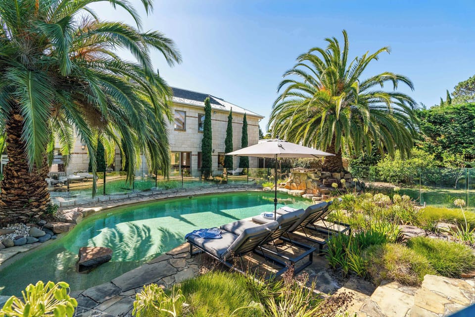 The private and exclusive solar heated, lagoon style pool, overlooked by the grand façade of the home 