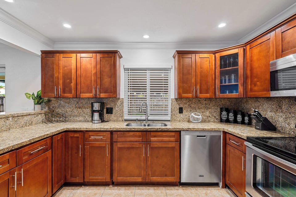 Kitchen with granite counters, sink, dishwasher and coffee maker.