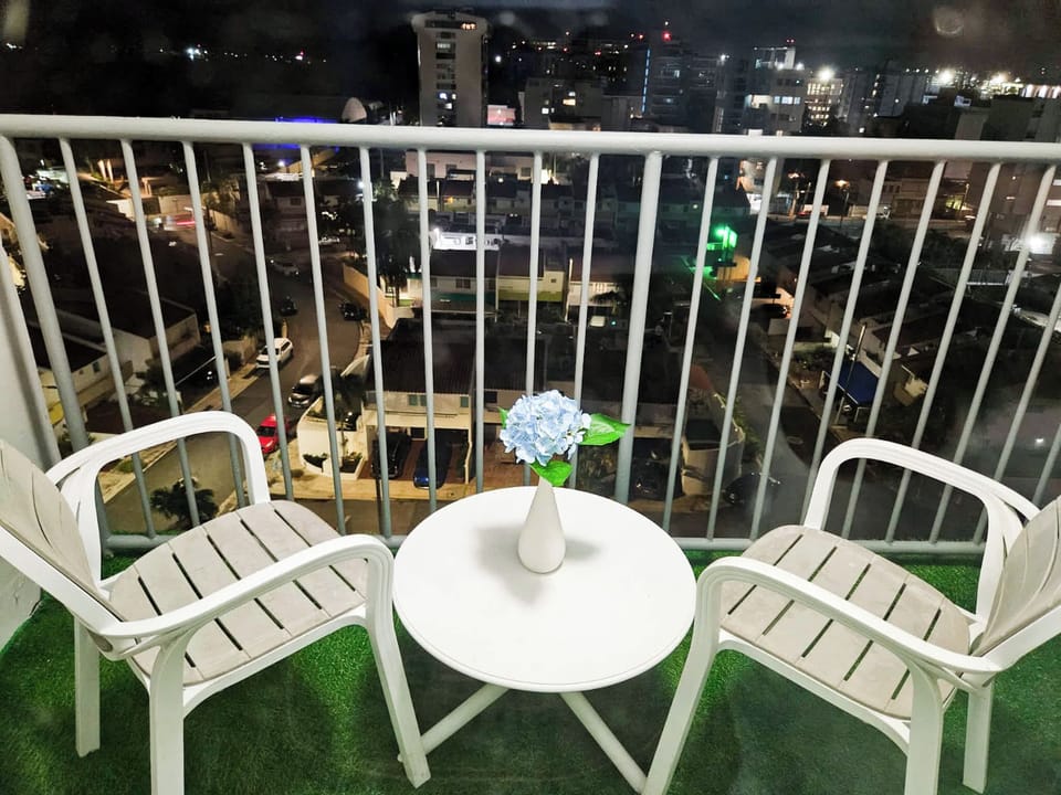 Charming balcony with cozy seating and a peaceful city view—perfect for enjoying your morning coffee or unwinding under the night lights.
