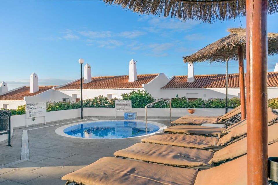 Poolside loungers under thatched umbrellas.