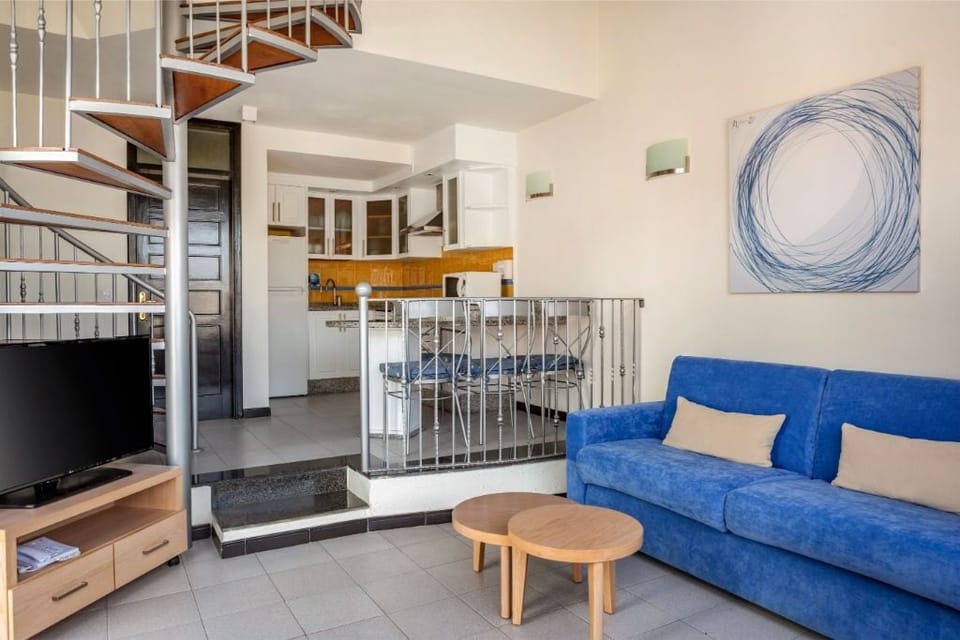 Relax in our open-plan living room with vibrant blue accents and ample natural light.